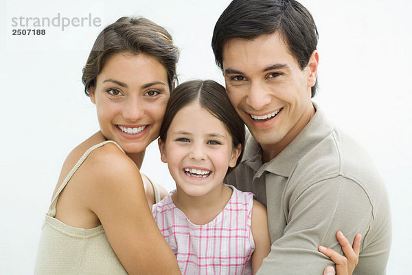 Junge Eltern mit Mädchen dazwischen  lächelnd vor der Kamera  Porträt