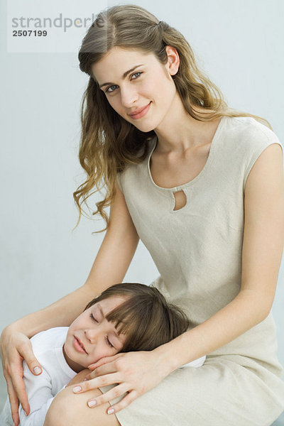Kleiner Junge ruht Kopf auf dem Schoß der Mutter  Frau lächelt vor der Kamera