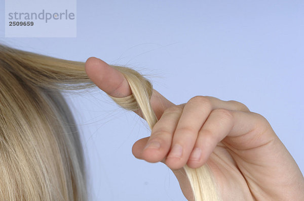 Weibliche Hand hält Haare  Nahaufnahme