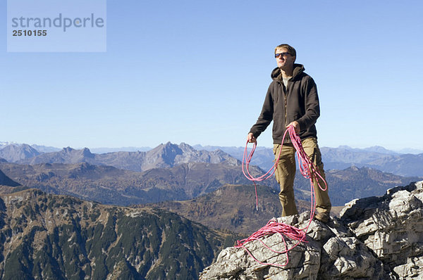Österreich  Salzburger Land  Junger Mann mit Seil gegen die Bergwelt