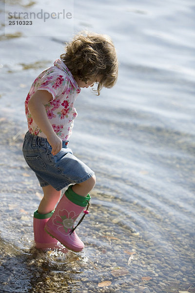 kleines Mädchen (3-4)  das am Strand spielt.