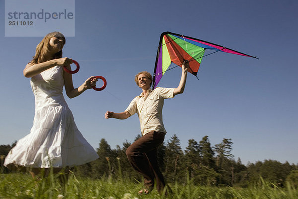 Deutschland  Bayern  Junges Paar Drachenfliegen auf der Wiese