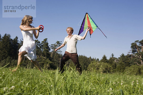 Deutschland  Bavaia  Junges Paar beim Drachenfliegen auf der Wiese