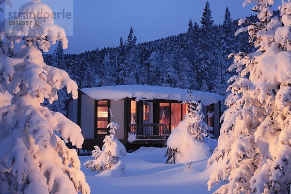View of La Mesange shelter and snow-covered trees at twilight  Quebec  Canada.