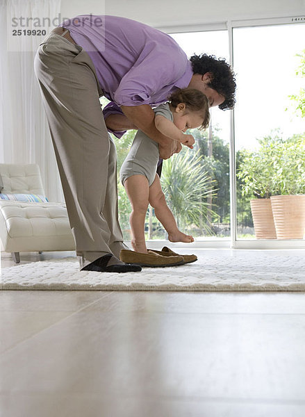 Vater steckt Baby in Schuhe zu Hause