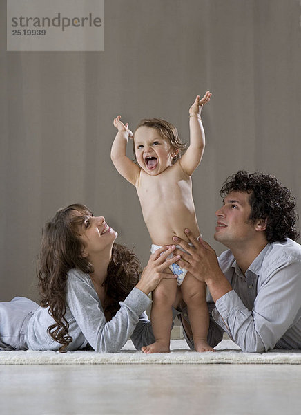 Eltern helfen dem Baby aufzustehen