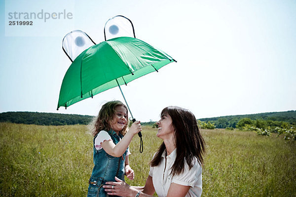 Frau und Mädchen spielen mit Regenschirm