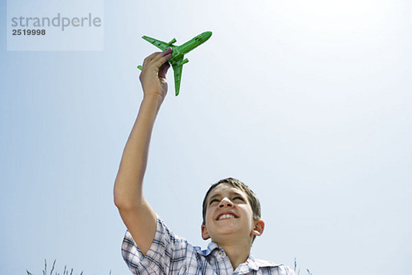 Junge hält Spielzeugflugzeug in der Luft