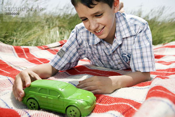 Junge spielt mit grünem Spielzeugauto