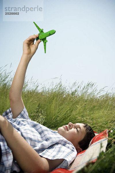 Junge im Liegen spielend mit dem Flugzeug