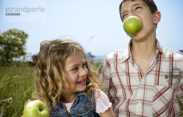 Junge hält Apfel in den Zähnen mit Mädchen