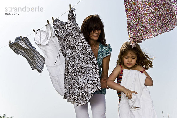 Mädchen helfen Mutter falten Kleidung