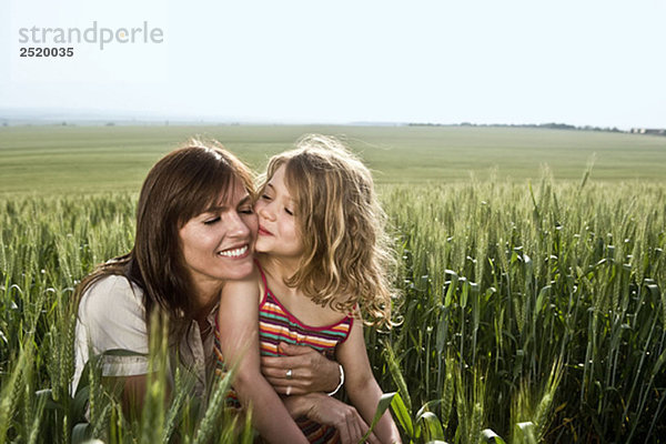 Kind küssende Mutter im Weizenfeld