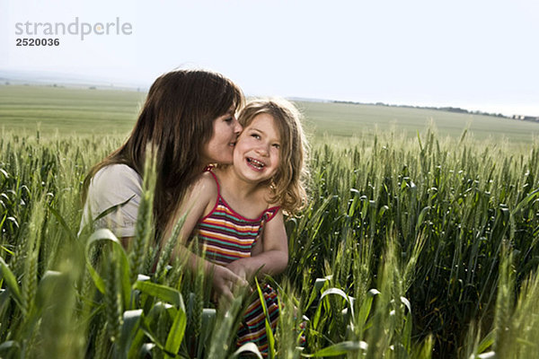 Mutter küssendes Kind im Weizenfeld