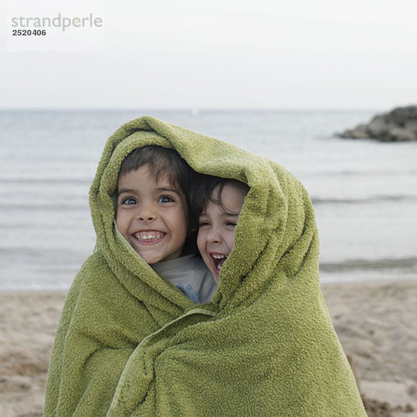 Zwei kleine Kinder im Handtuch am Strand