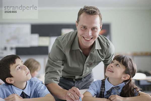 Männlicher Lehrer korrigiert Schülerarbeit