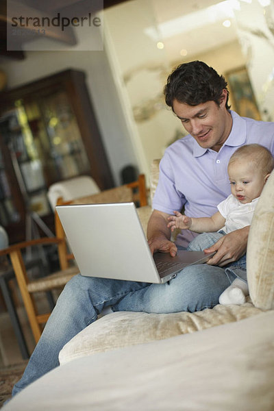 Vater sitzend am Laptop mit jungem Sohn