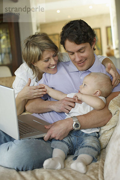 Junge Familie auf Sofa mit Laptop