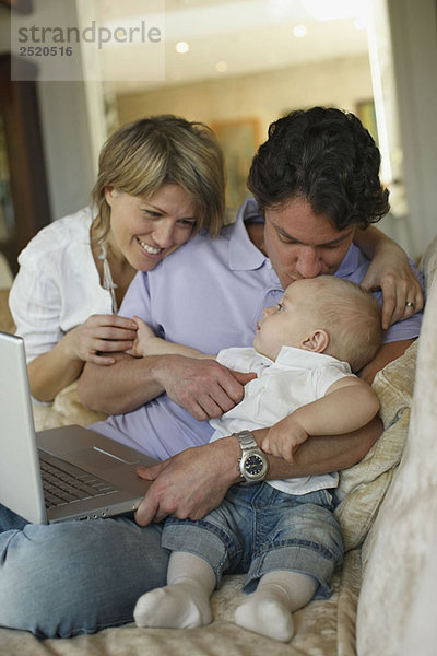 Junge Familie auf Sofa mit Laptop