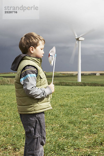 Junge bläst Windmühle auf einem Windpark