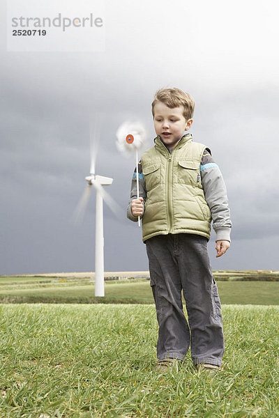 Junge mit Windmühle auf einem Windpark