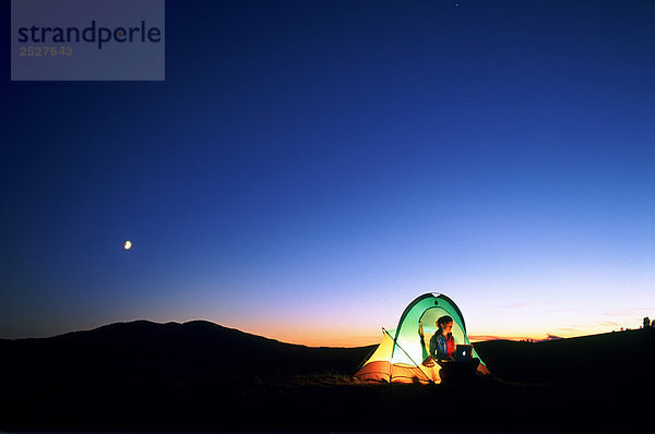 Frau im Zelt in der Nacht mit Laptop  British Columbia.