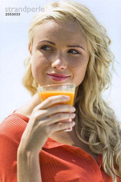 Porträt einer jungen blonden Frau mit einem Fruchtsaftglas