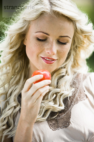 Junge Frau hält eine Tomate in der Hand