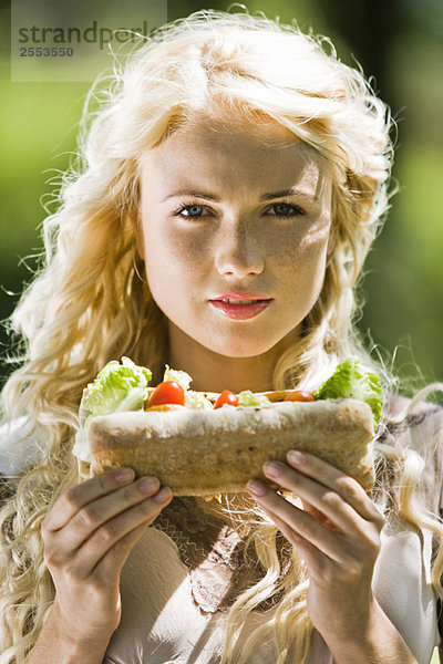 Porträt einer jungen blonden Frau mit einem Sandwich