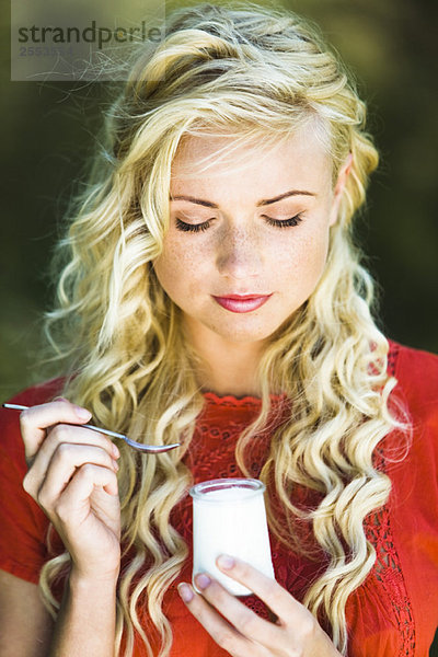 Porträt einer jungen Frau beim Joghurtessen