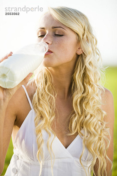 Junge Frau trinkt Milch aus der Flasche