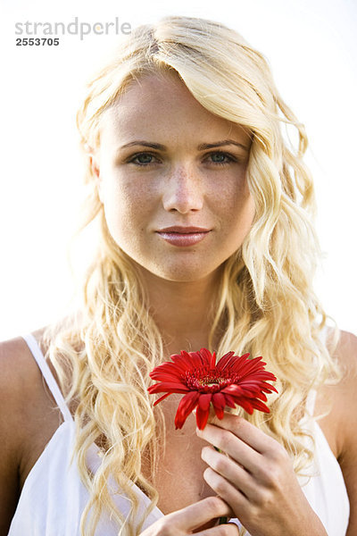 Porträt einer jungen Frau mit roter Blume