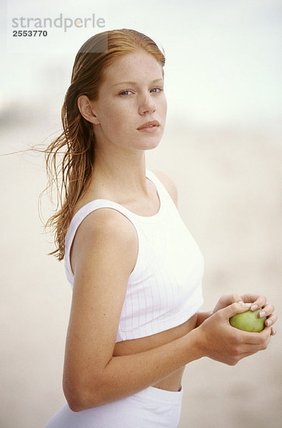 Junge Frau hält einen Apfel  im Freien