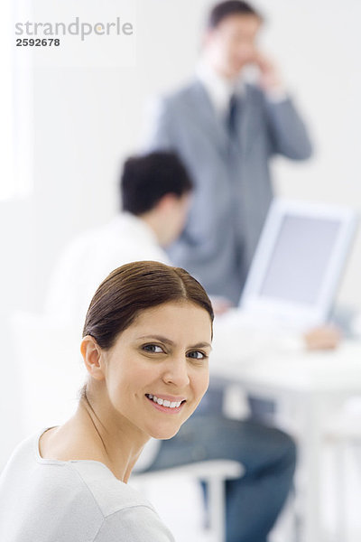 Professionelle Frau im Büro  über die Schulter lächelnd vor der Kamera