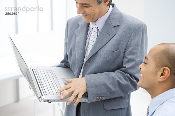 Zwei Geschäftsleute  die zusammen auf den Laptop schauen  beide lächelnd