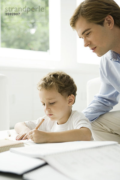 Vater hilft dem jungen Sohn bei den Hausaufgaben