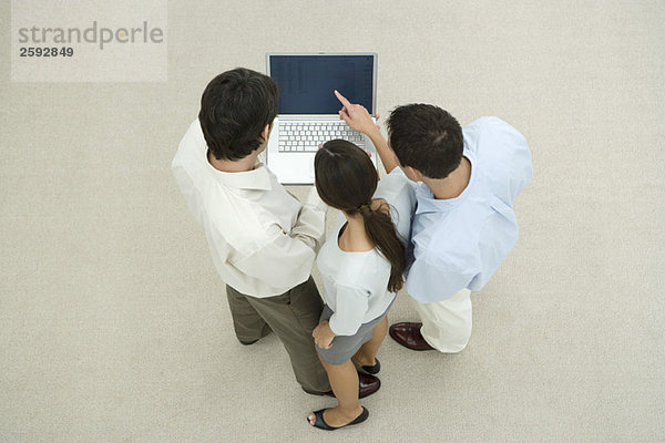 Drei Profis im Stehen  gemeinsam auf den Laptop schauen  hohe Blickwinkel