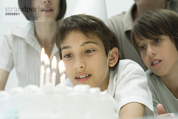 Junge wünscht sich etwas  bevor er Kerzen auf dem Geburtstagskuchen ausbläst.