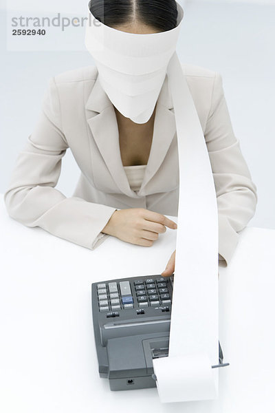 Geschäftsfrau mit Addiermaschine  Augenbinde mit Papierausdruck