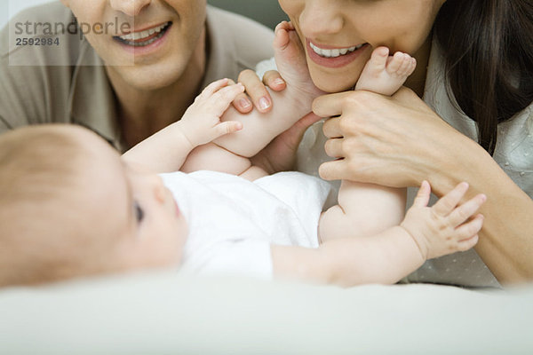 Eltern lächeln das Baby an  Mutter hält die Füße des Babys  Ausschnittansicht
