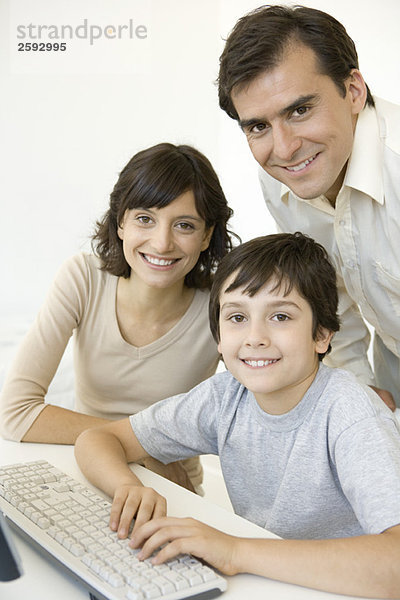 Junge mit Eltern  mit Tastatur  alle lächelnd vor der Kamera
