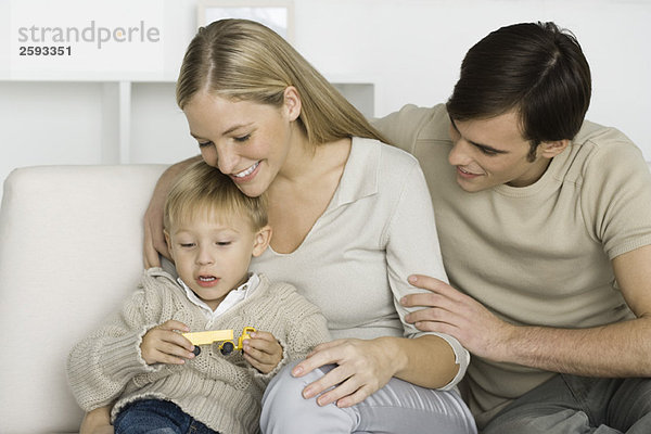 Eltern und junger Sohn beim Anblick des Spielzeug-LKWs  lächelnd