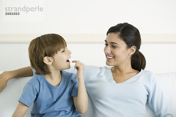 Mutter und Sohn sitzen zusammen  der Junge zeigt auf den offenen Mund.