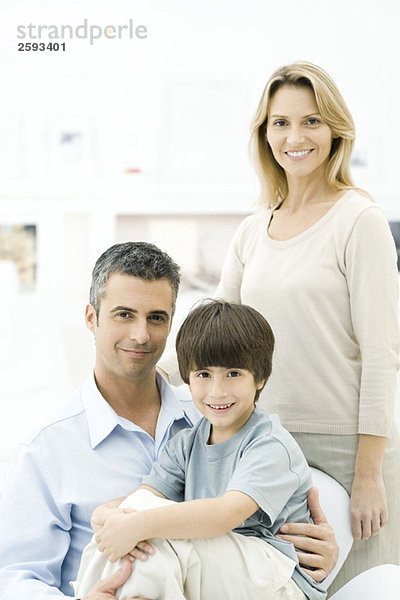 Familie lächelt vor der Kamera  Junge sitzt auf Vaters Schoß