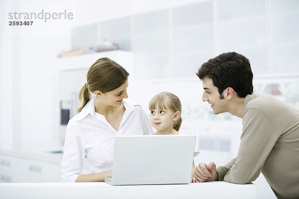 Familie versammelt um Laptop-Computer  lächelnd  Mädchen sucht Mutter