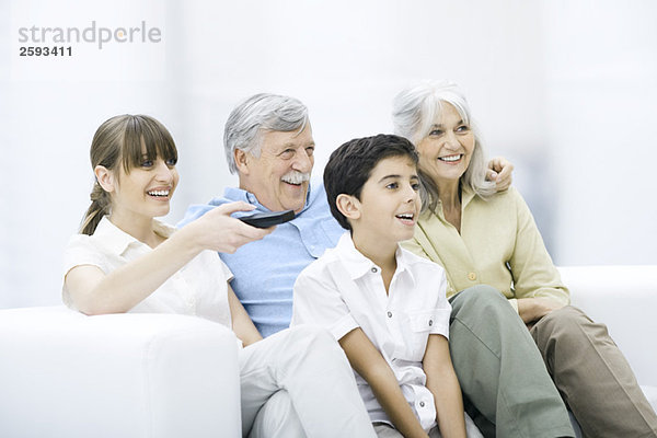 Mehrgenerationen-Familie  die zusammen auf dem Sofa sitzt und fernsieht.