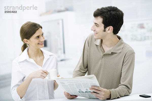 Paar lächelt sich an  Mann hält Zeitung  Frau hält Kaffeetasse