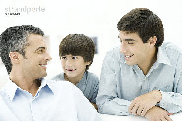 Vater und zwei Söhne lächeln sich an  Nahaufnahme