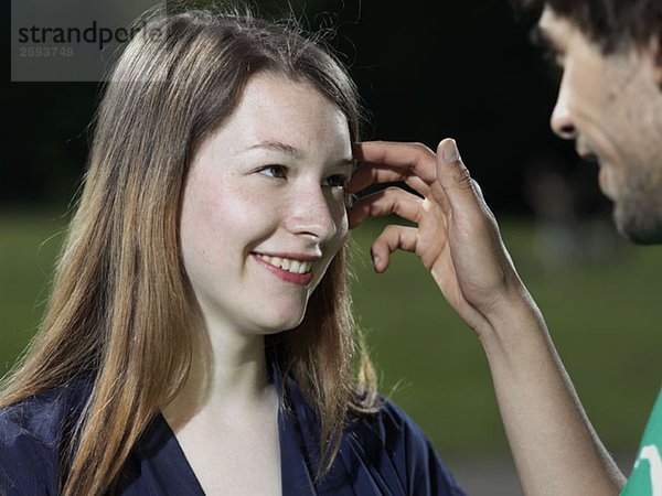 Ein junger Mann schiebt die Haare aus dem Gesicht einer jungen Frau zurück.
