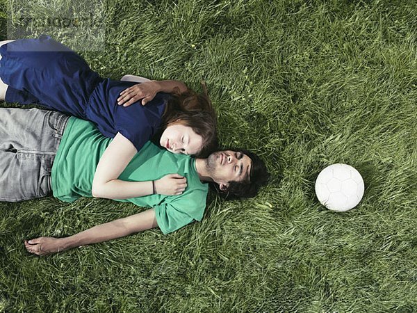Ein junges Paar  das im Gras liegt und schläft.